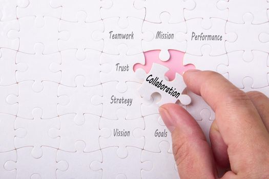 Management concept with hand holding piece of jigsaw puzzle with Collaboration wording