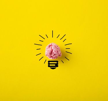 Inspiration concept crumpled paper light bulb metaphor for good idea on yellow background