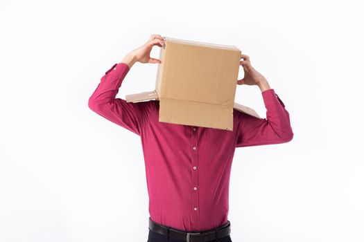 man in a red shirt with a cardboard box on his head makes a gesture with his hands isolated on white background