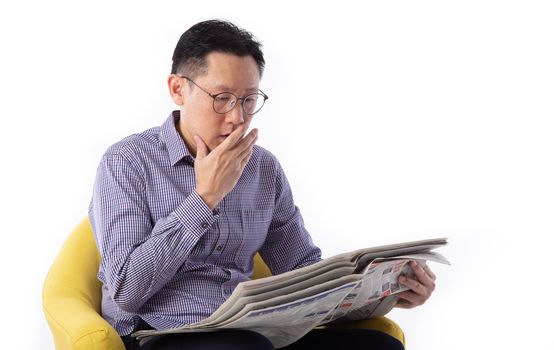Surprised man reading the news seated on a bench isolated on white background