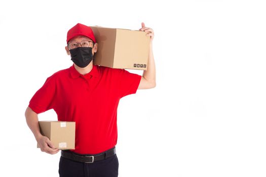 young Asian delivery man in red uniform with  face mask, carrry cardboard box in hands isolated on white background. Delivery concept