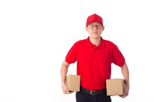 young Asian delivery man in red uniform, carry cardboard box in hands isolated on white background. Delivery Concept