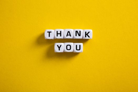 Block with word Thank You on yellow background