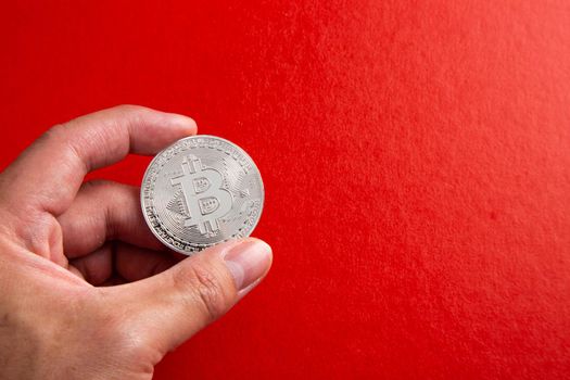 Man Hand holding a bitcoin on red background