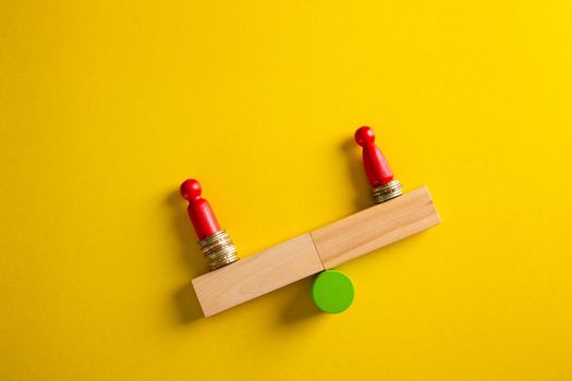 Gender pay gap. Wooden cubes with male and female gender signs on seesaw with different stacks of coins, men outweigh,