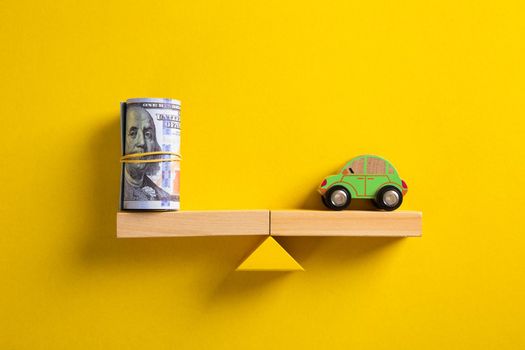 Car / Auto loan or transforming assets into cash concept : Car model, US dollar notes in jute bags on simple balance scale, depicts car owner or borrower turns personal properties into cash or wealth.