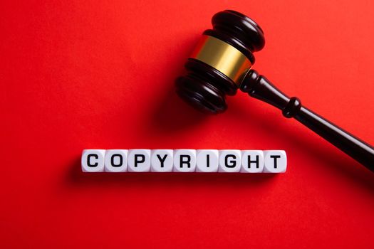 Copyright word and a judge gavel on red background. Concept of legal education.