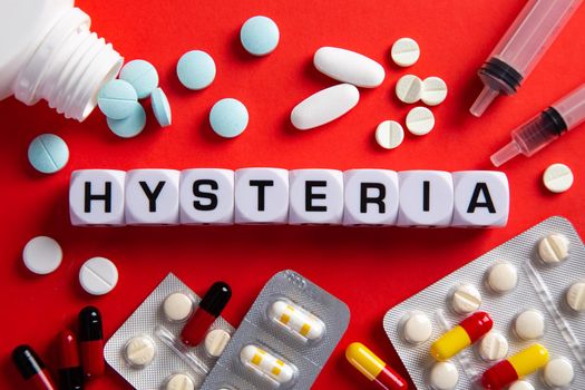 Hysteria medicine word on blocks on red background. Medical concept with pills, vitamins and syringe on the background.