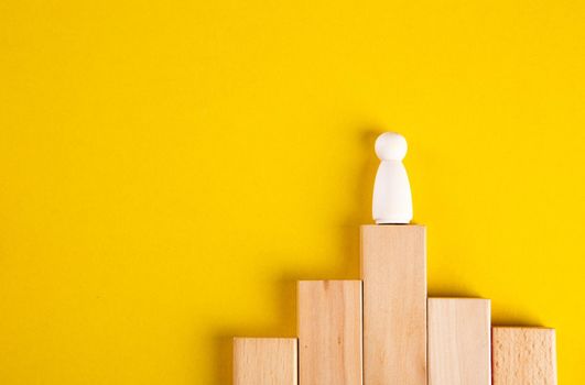 Wooden figures on yellow background. Concept of supremacy leader