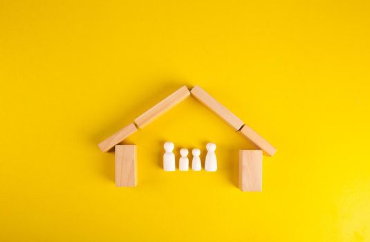 Wooden pegs in a shape of a house to shelter a family made of wooden. Family insurance protection onceptual.