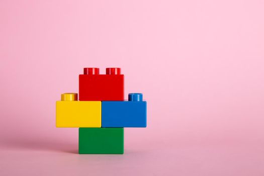 Plastic building blocks on pink background