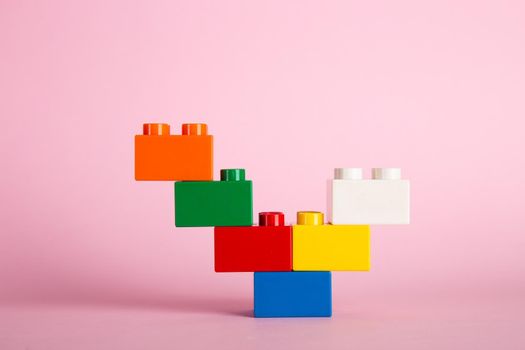Plastic building blocks on pink background
