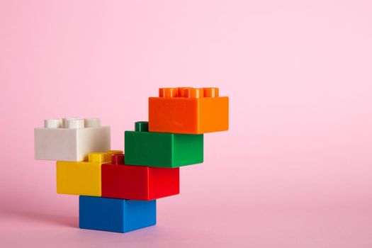 Plastic building blocks on pink background