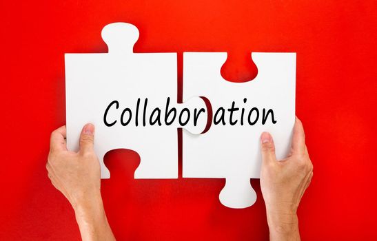 Two hands connect puzzles on a red background. Cooperation and teamwork in business. Collaboration people for success.