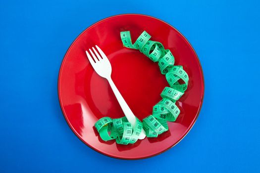 Diet for weight loss concept. Proper nutrition. Empty plate with fork and measuring tape.