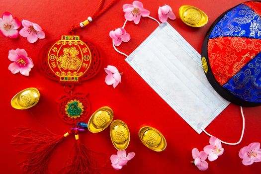 Face mask and Chinese ancient ingot and flowers on red color. Chinese new year background and health care medical concept