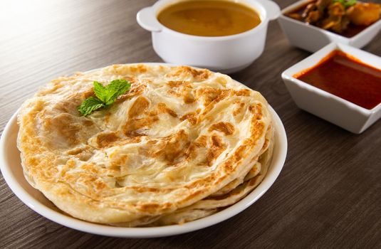 Roti Parata or Roti canai with lamb curry sauce - popular Malaysian breakfast