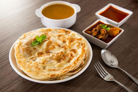 Roti Parata or Roti canai with lamb curry sauce - popular Malaysian breakfast