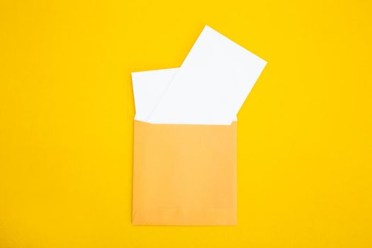 Colorful paper envelopes on yellow background - top view
