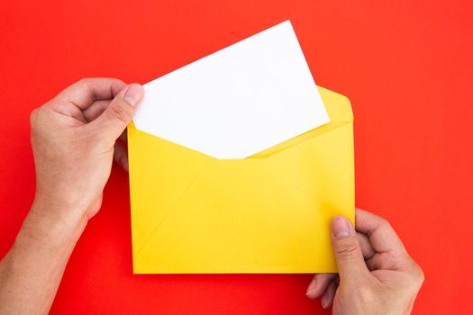 Hand holding a blank white card in color envelope