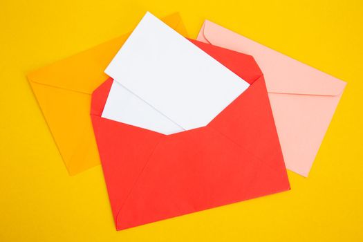 Colorful paper envelopes on yellow background - top view