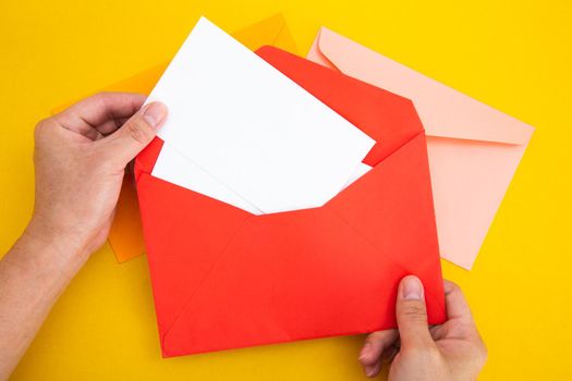 Hand holding a blank white card in color envelope