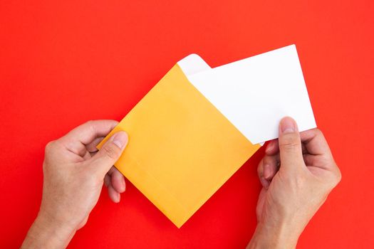 Hand holding a blank white card in color envelope