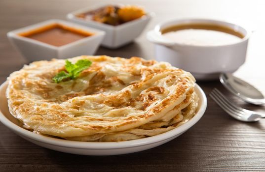 Roti Parata or Roti canai with lamb curry sauce - popular Malaysian breakfast