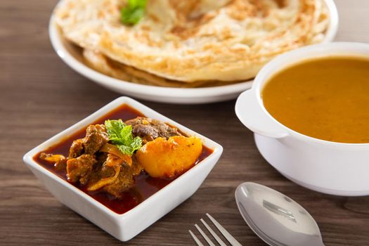 Roti Parata or Roti canai with lamb curry sauce - popular Malaysian breakfast