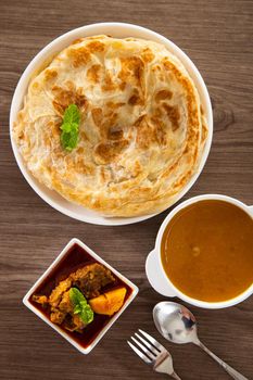 Roti Parata or Roti canai with lamb curry sauce - popular Malaysian breakfast