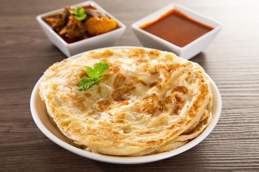 Roti Parata or Roti canai with lamb curry sauce - popular Malaysian breakfast
