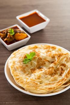 Roti Parata or Roti canai with lamb curry sauce - popular Malaysian breakfast