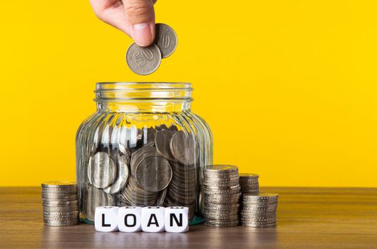 A lot coins in glass money jar with yellow background. Saving for Finance concept.