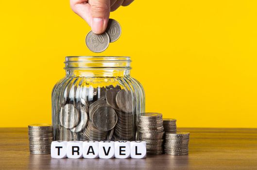 A lot coins in glass money jar with yellow background. Saving for Travel concept.