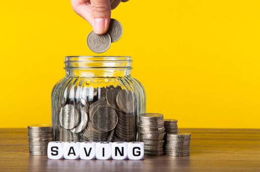 A lot coins in glass money jar with yellow background. Saving for Investment concept.