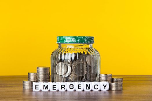 A lot coins in glass money jar with yellow background. Saving for Saving concept.