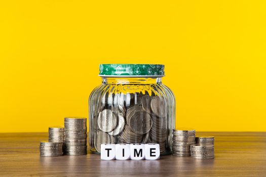 A lot coins in glass money jar with yellow background. Saving for Investment concept.