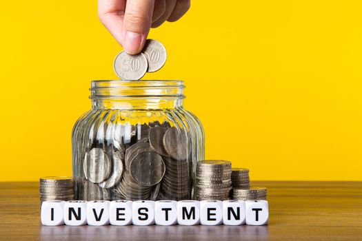 A lot coins in glass money jar with yellow background. Saving for Investment concept.