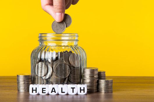 A lot coins in glass money jar with yellow background. Saving for Health concept.