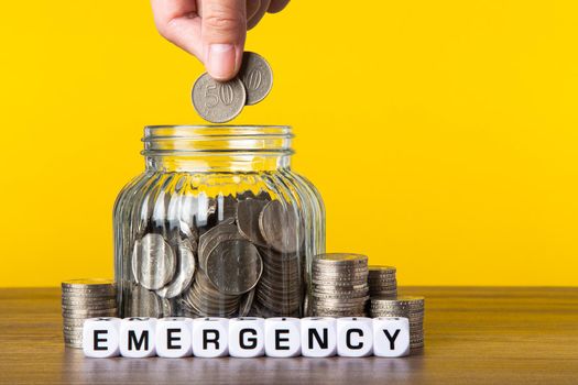 A lot coins in glass money jar with yellow background. Saving for Saving concept.
