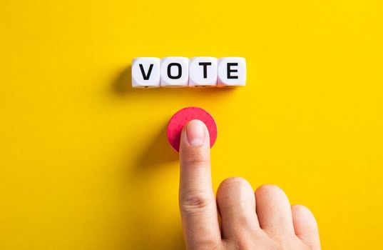 Hand with word vote on yellow background. Voting in political election or in business concept.