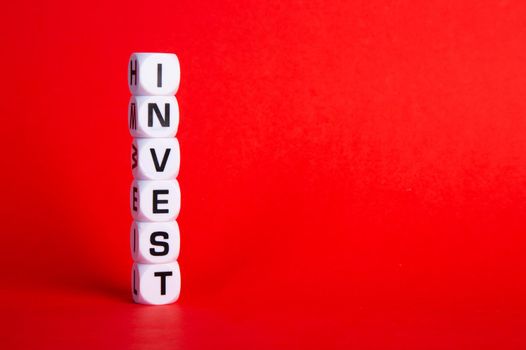 The word invest on cubes against red background. Financial investment growth or investment decision in business concept.