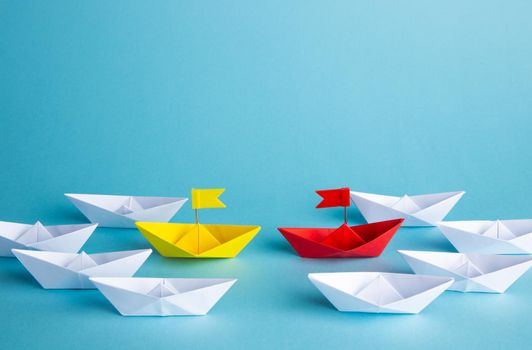 Leadership concept. Red leader paper ship leading among others on blue background.