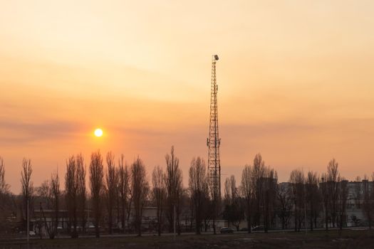 The tower of the mobile network operator at sunset. Urban landscape.