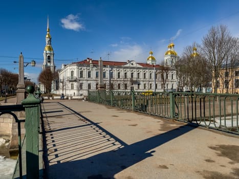 Russia, St. Petersburg, 01 April 2021: St. Nicholas Naval Cathedral belltower in a clear sunny day of spring, an ice drift on Kryukov and Griboyedov Canal, a view of seven bridges from the embankment. High quality photo
