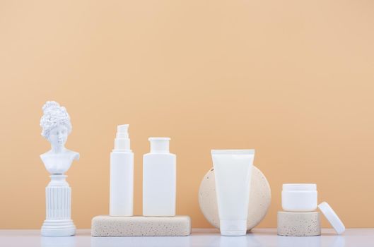 Set of skin care products with gypsum figure of a woman on white table against beige background with copy space. Products for daily skin care