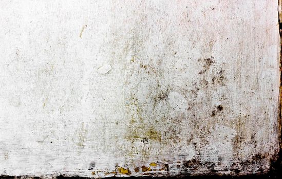 A heavily textured white wall showing signs of weathering and slight decay. A little bit of yellow paint shows through some of the white.