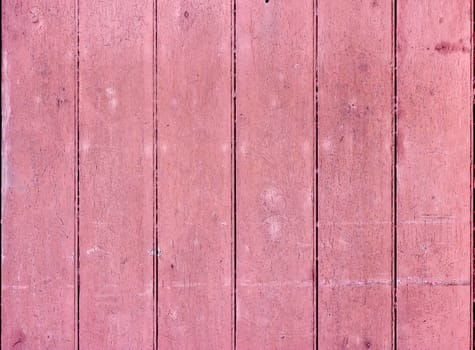 Vertical strips of wood painted pink. The paint is old and cracked.