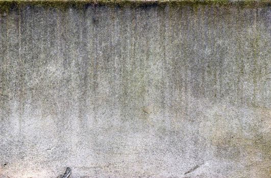 Vertical lines of dirt streak down a white heavily textured concrete wall.
