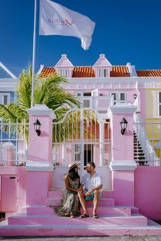Curacao, Netherlands Antilles View of colorful buildings of downtown Willemstad Curacao Colorful restored colonial buildings in Pietermaai, couple men and woman mid age posing by colorful buildings
